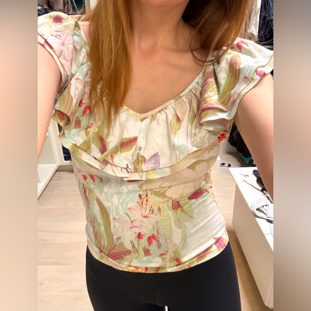 A blouse with soft, floral print with pastel tones, ruffled neckline.